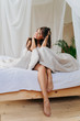 © Yakobchuk Olena - Smiling lady is sitting with a blanket on bed