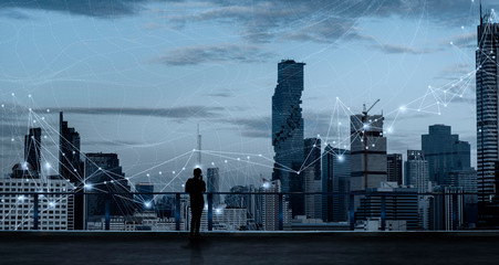 Fototapete - Businessman standing using smart phone in modern space watching city night view.Business Wireless network and Connection technology concept.