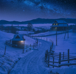 Wall Mural - Snowy road through the alpine village at night