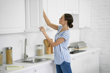 Woman Opening The Kitchen Cupboard Stock Photo
