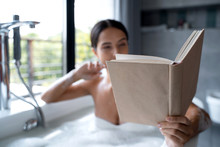 Female Reading A Book In A Bath