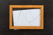 Wooden frame with broken glass on a dark surface.