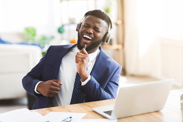 Handsome businessman singing and listening to music with headphones