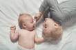 © somemeans - Baby and smiling older brother are lying on the bed. Funny and interact. Top view