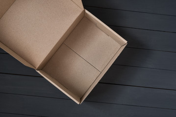 Empty open cardboard box on black wooden background. Delivery concept. Top view