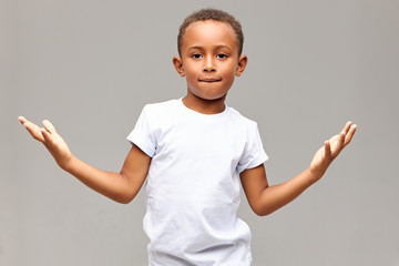 Poster - Children, lifestyle and body language. Isolated shot of cool handsome African American little boy having confident look biting lower lip and making gesture with palms, showing he is not afraid