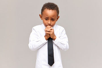 Poster - Portrait of nervous frustrated sad African American schoolboy in uniform looking down with worried facial expression, gnawing nails, scared of being told off for bad marks at school. Sincere emotions