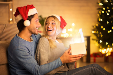 Excited couple opening Christmas gift in living room