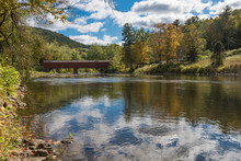 Wooden Covered Bridge In Cornwall, Connecticut, USA Showing Reflections Of Sky And Forest On Beautiful Early Fall Day