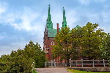 Wall Mural - Helsinki. Finland. St. John Church in Helsinki. Lutheran Church in Helsinki. Church on the background of green trees. Religious building. Brick Cathedral with a green roof.