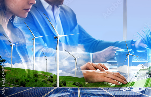 Double exposure graphic of business people working over wind turbine farm and green renewable energy worker interface. Concept of sustainability development by alternative energy.