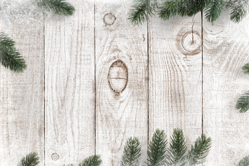 pine leaves decorated as a frame on a white wooden background with snowflakes. merry christmas and w
