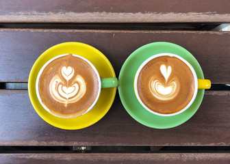 Hot Coffee Latte in colourful cup and saucer on rustic wooden table