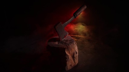 Wall Mural - Old ax attached to the tree trunk on horror red foggy background. Scary Halloween theme with maniac killer weapon. Empty space. Selective focus