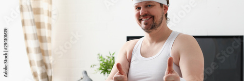 Fotografía Young attractive man engaged in fitness at home holding dumbbell in hand trying