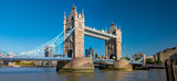 Fototapeta Londyn - Panorama view of the Tower bridge over Thames river on a sunny day with the City Financial district skyscrapers and Tower of London in the background.