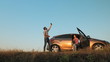 © DiedovStock - Man and woman traveling by car catches a phone signal while standing on the side of the road