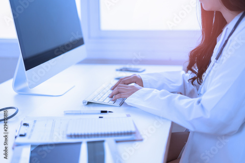 Asian Female Doctor Sitting At Hospital Office Desk Giving All