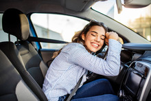 Young And Cheerful Woman Enjoying New Car Hugging Steering Wheel Sitting Inside. Woman Driving A New Car. Woman Driver Portrait At Car