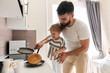 bearded father helping child to turn over the pancake in the kitchen, close up photo.