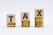 © MuhaiminAzfar - Tax concept with wooden block on stacked coin