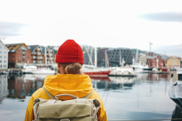 Wall Mural - Alone traveler walk the city streets with pier view. Back view of man tourist with backpack standing on berth while journey