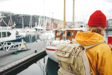 Wall Mural - Alone traveler walk the city streets with pier view. Back view of man tourist with backpack standing on berth while journey