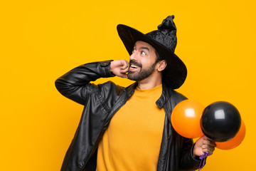 Wall Mural - Man with witch hat holding black and orange air balloons for halloween party thinking an idea