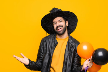 Wall Mural - Man with witch hat holding black and orange air balloons for halloween party smiling