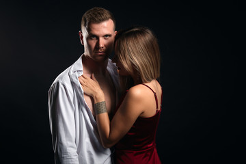 Wall Mural - blonde elegant woman touching her boyfriend. close up portrait, isolated black background, amorous adventure