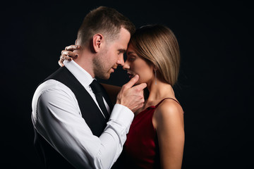 Wall Mural - sexy young elegant couple in the tender passion, close up side view photo. isolated black background, studio shot. romance, desire