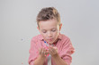 © iwavephoto - Сheerful brunette boy blows to confetti over grey background, concept of children's emotions and holiday