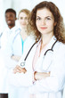 © rogerphoto - Happy doctor woman with medical staff at the hospital. Multi ethnic people group