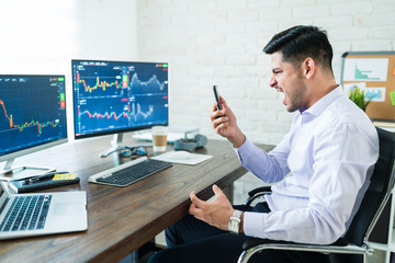 Wall Mural - angry broker shouting at smartphone for wrong transaction