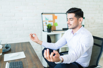 Wall Mural - businessman meditating while sitting on chair