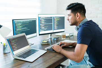Wall Mural - handsome young male programmer coding at desk