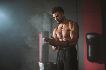 concentrated bodybuilding man take some powder on his hands and get ready to start a intense workout