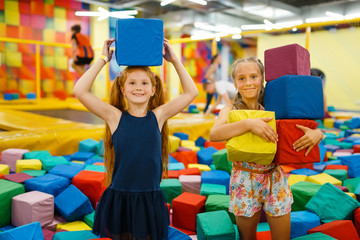 Two little girls playing with soft cubes, playroom