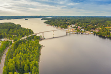 Sticker - Aerial view on the bridge over the lake and trees in the forest on the shore. Blue lakes, islands and green forests from above on a cloudy summer day. Lake landscape in Finland, Puumala.