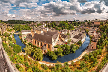 Wall Mural - Panoramic view of the Church of St Jean du Grund and the old town in the valley of the river Alzette. Travel destinations in tiny country of Luxembourg