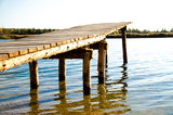 Fototapeta Pomosty - wooden bridge on the lake on a summer day with a blue ode