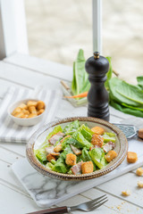 Fresh Green organic Caesar salad on the white wooden table.