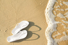 White Flip Flops On Sand Near Sea, Space For Text. Beach Accessories