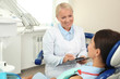 © New Africa - Professional dentist working with patient in clinic
