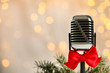 © New Africa - Microphone with red bow and fir branches against blurred lights, space for text. Christmas music