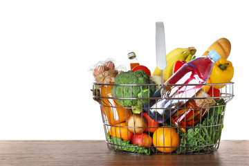 Poster - Shopping basket with grocery products on wooden table against white background. Space for text