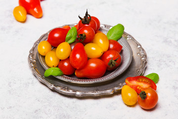 Wall Mural - Colorful organic cherry tomatoes on silver plates, light background.