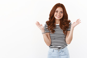 Sorry my bad. Cute silly redhead girl in striped t-shirt raising hands up in surrender, apologizing for slight inconvenience, mistake, smiling embarrassed and shy, white background