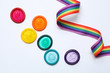 Colorful condoms and rainbow ribbon on white background, top view. LGBT concept
