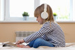 © AnastazjaSoroka - Little blond girl streaming online on tablet with headset.